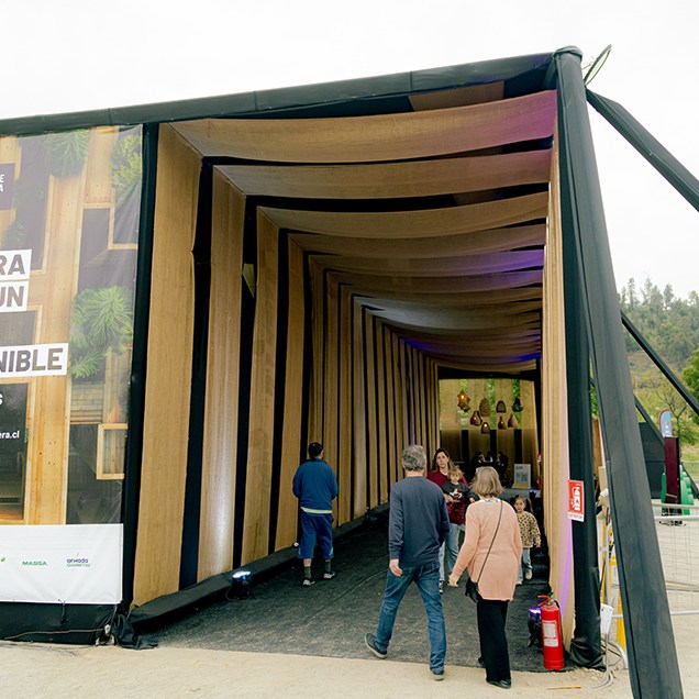 2. La Sostenibilidad y Arquitectura: Stands de Madera Renovable Esta fotografía representa el compromiso con la Economía Circular y la Sostenibilidad Operacional. Muestra la infraestructura del evento en el Parque Bicentenario, destacando los 1.000 stands construidos con 100% madera renovable, suministrada por el auspiciador ARAUCO. Refleja la masividad del evento y su impacto ambiental consciente.